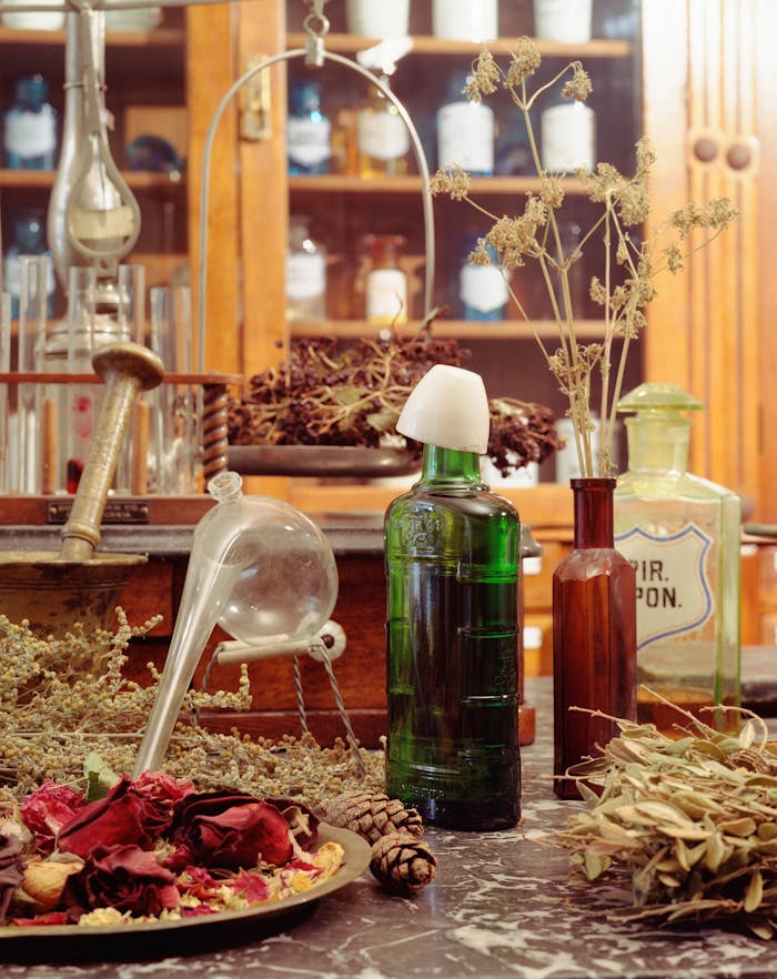 A rustic apothecary setup featuring vintage bottles, dried herbs, and glassware in a warm, nostalgic setting.